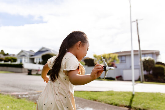 Young Samoan girl holding a toy aeroplane running outdoors - travel concept