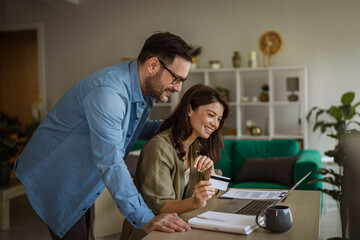 Obraz premium Couple shopping online using credit card and laptop at home