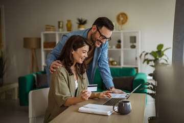 Obraz premium Couple shopping online using credit card and laptop at home