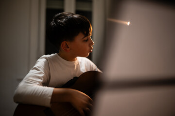 Young boy learning playing acoustic guitar concentrating
