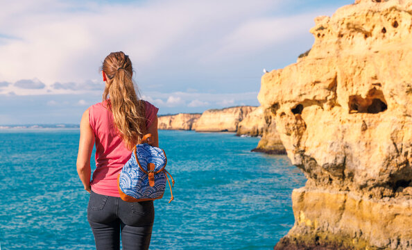 Woman enjoying beautiful view of cliff, cave and rocj formation, Algarve in Portugal