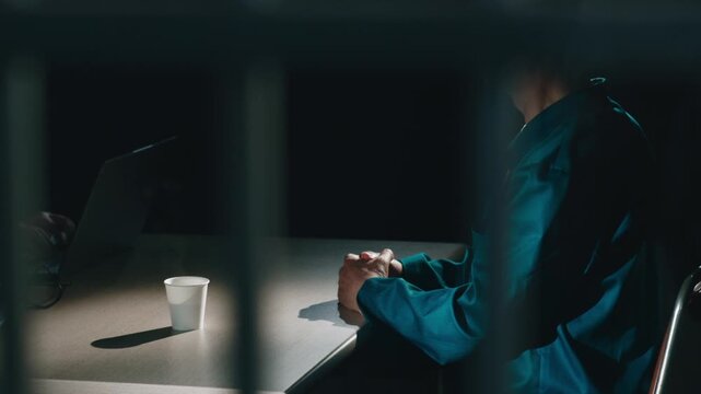 Detective hands coffee to suspect in dark room.