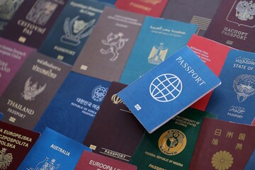 Fictional passport book travel document on big amount of real passport covers of various different countries. Expired passports in big pile close up. Travel documents for tourism