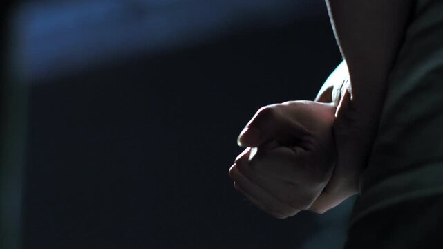 Person's hand with backpack on dark background