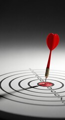 Red dart hitting bullseye on target board representing precision and success © Mimie
