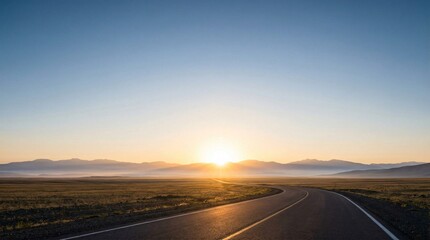 A winding asphalt road leads across a vast open landscape towards a bright sunrise over distant mountains © Mimie