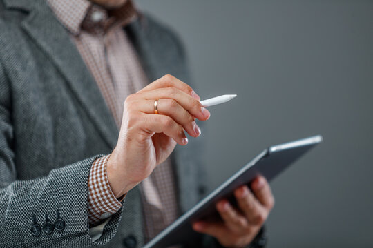 Close-up of businessman holding stylus and tablet signing digital document in modern office setting