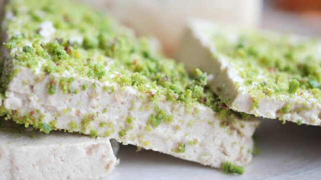 Close up of delicious tahini halva with chopped pistachios dusted on top in slow motion