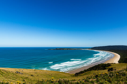 Sweeping view over bay with rolling waves and deep blue ocean