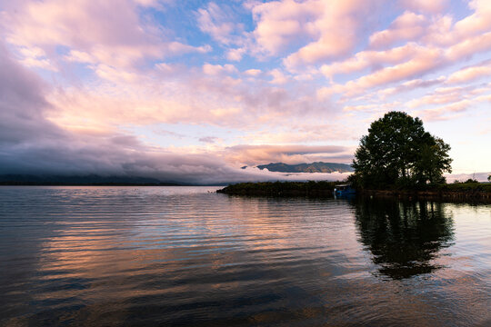 Sunrise coloured cloud patterns reflected in a tranquil lake