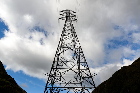 Electrical transmission tower silhouetted against cloudy sky