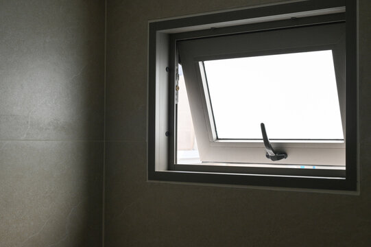 Open bathroom window modern gray tile wall natural light ventilation minimalist style clean simple rectangular shape black handle interior design