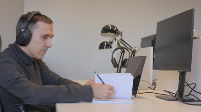 Calm programmer working on laptop with handwritten notes in natural light