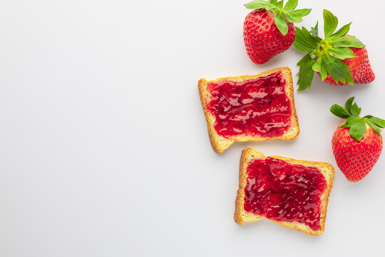 Strawberry jam on toast with fresh strawberries placed on a clear background