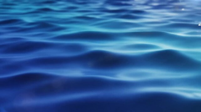 Calm ocean water surface with subtle waves and blue and teal color gradients, creating a serene ambiance