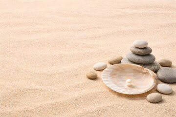 Obraz premium The scene shows stacked stones next to a large shell holding a pearl. The background features smooth sand at a beach area, typical of midday light
