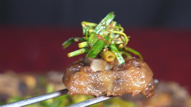 Chopsticks holding boiled oxtail with green onions and sauce