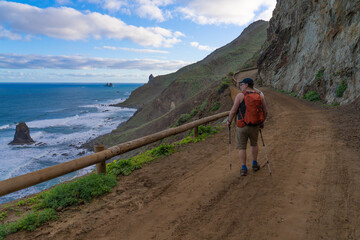 Fototapeta premium A hiker walks along the road by the Ocean. Tenerife. Anaga Rural Park.