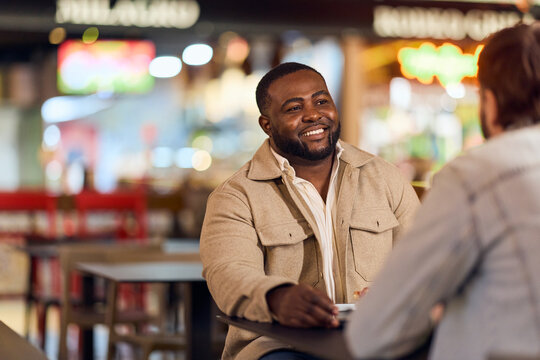 Friendly Conversation Between Friends At A Casual Cafe With An African-American Man Smiling