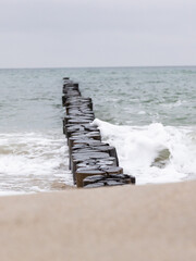 Fototapeta premium Winterliche Ostseewellen treffen im Februar 2026 bei Hohe Düne auf Buhnen und Strand.