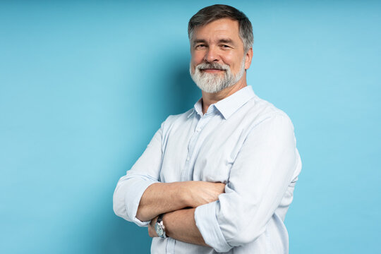 Portrait of happy casual older man smiling, Mid adult, mature age male with gray hair, Isolated on blue background