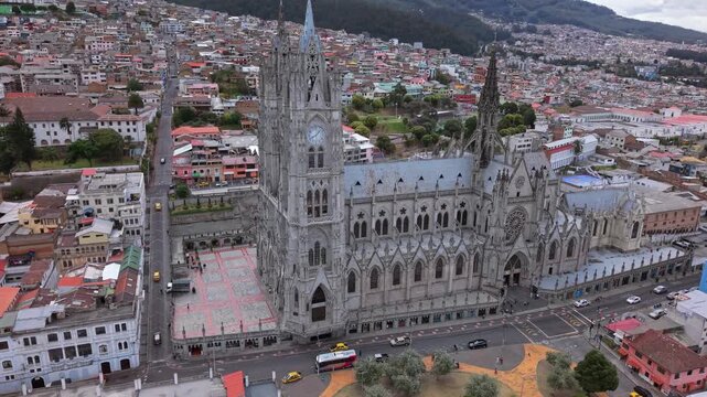 Drone arcs around Basilica of the National Vow revealing main neo-Gothic facade and historic Quito cityscape