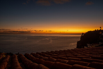 zachód słońca widziany ponad dachem pokrytym ceramiczną dachówką, Madera, Ocean Atlantycki © Kamil_k2p