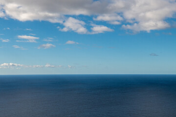 Fototapeta premium Spokojny horyzont oceanu pod błękitnym niebem z chmurami