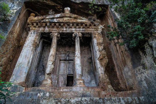 Ancient Lycian rock tomb of Amyntas in Fethiye, Turkey. Scenic low angle view of the monumental stone facade with ionic columns carved into a cliff. Historical heritage and antique architecture.
