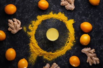  curcuma cocktail decorated with Curcuma powder with ripe lemons and gingers at black table. flat lay. Healthy concept