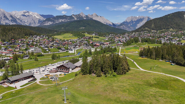 aerial, bird view, Seefeld, Austria. View on Seefeld in Tirol village, in the valley between impressive alpine mountains. View from grassy hill on the town, pine tree at the side. Beautiful tourist mu