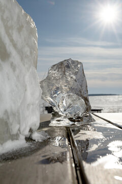 Large natural pond ice blocks on a wooden surface under bright sun symbolizing climate change and environmental purity
