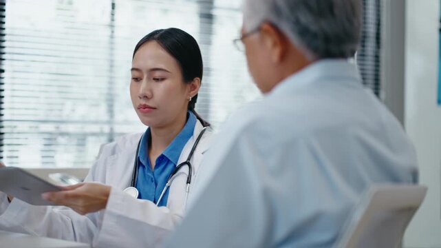 Asian senior man having health consultation and check up and  with female doctor at clinic.woman doctor examine elderly Asian man patient use stethoscope listening to the sounds of heart and lungs.
