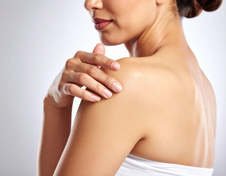 Close up of woman touching bare soft skin on her shoulder