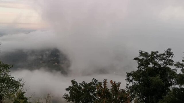 Fog envelops the landscape of Calascibetta, revealing glimpses of trees and hills in the Province of Enna, Sicily, creating a mystical atmosphere in the clouds