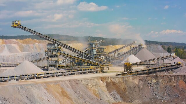 Large mineral processing plant with crushing and grinding machinery operating in quarry landscape