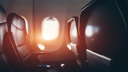 Airplane cabin interior with row of seats and window illuminated by sunlight travel concept, Aircraft passenger seating inside modern airline cabin showing empty chairs and bright porthole at flight
