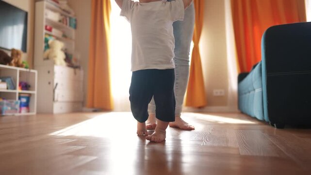 Baby is taking the first steps. happy family kid dream concept. Mom and baby taking the first steps. family together Mom taking the first fun steps with her baby. toddler. first steps concept.