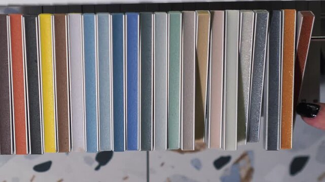 female designer applies epoxy grout samples to tiles and selects the desired color. tile grout color selection. bathroom renovation, tile work, professional interior design, catalogs