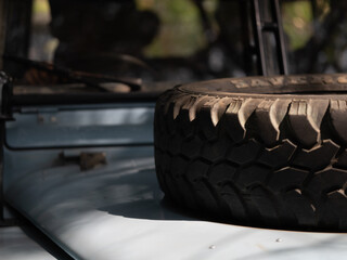 Close-up of a rugged spare tire mounted on the hood of a vintage off-road 4x4 vehicle. © Alif