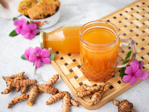 Indonesian herbal drink for health, or jamu called kunyit asam, made with turmeric, palm sugar, and tamarind; served in a glass or bottle.