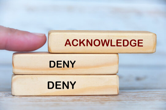 Acknowledge and Deny text on wooden blocks highlighting accountability versus avoidance in leadership culture.