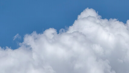 Naklejka premium A picturesque display of majestic fluffy white clouds gracefully drifting across a vibrant clear blue sky, evoking a sense of calm and natural beauty