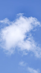 Obraz premium A tranquil and clear bright blue sky adorned with a single fluffy white cloud, evoking feelings of serenity and peacefulness on a beautiful day, offering a sense of openness and natural beauty