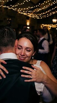Caucasian woman crying and embracing a man at a party with string lights, showing emotional connection and wedding day happiness
