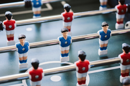 Table football players on foosball game field. Miniature team figures on metal rods. Recreational tabletop soccer match setup. Indoor entertainment and leisure activity concept.