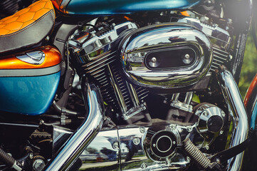 Obraz premium A horizontal close-up shot showing the intricate details of a custom motorcycle, including a chrome engine, heat-shielded exhaust, and a brown leather honeycomb-patterned seat. Highlights the contrast