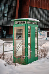 Obraz premium A Polish telephone box with TELEFON written on the side in green in the snow of winter.