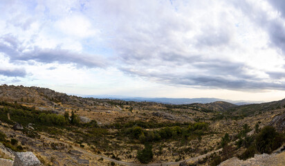 Fototapeta premium Wide panoramic landscape of Serra da Estrela mountains near Covilha with granite hills and dramatic cloud formation, Portugal, Covilha, 15 October 2025