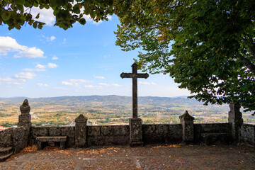 Historic stone cross viewpoint overlooking Covilha valley framed by trees in Serra da Estrela region, Portugal, Covilha, 15 October 2025